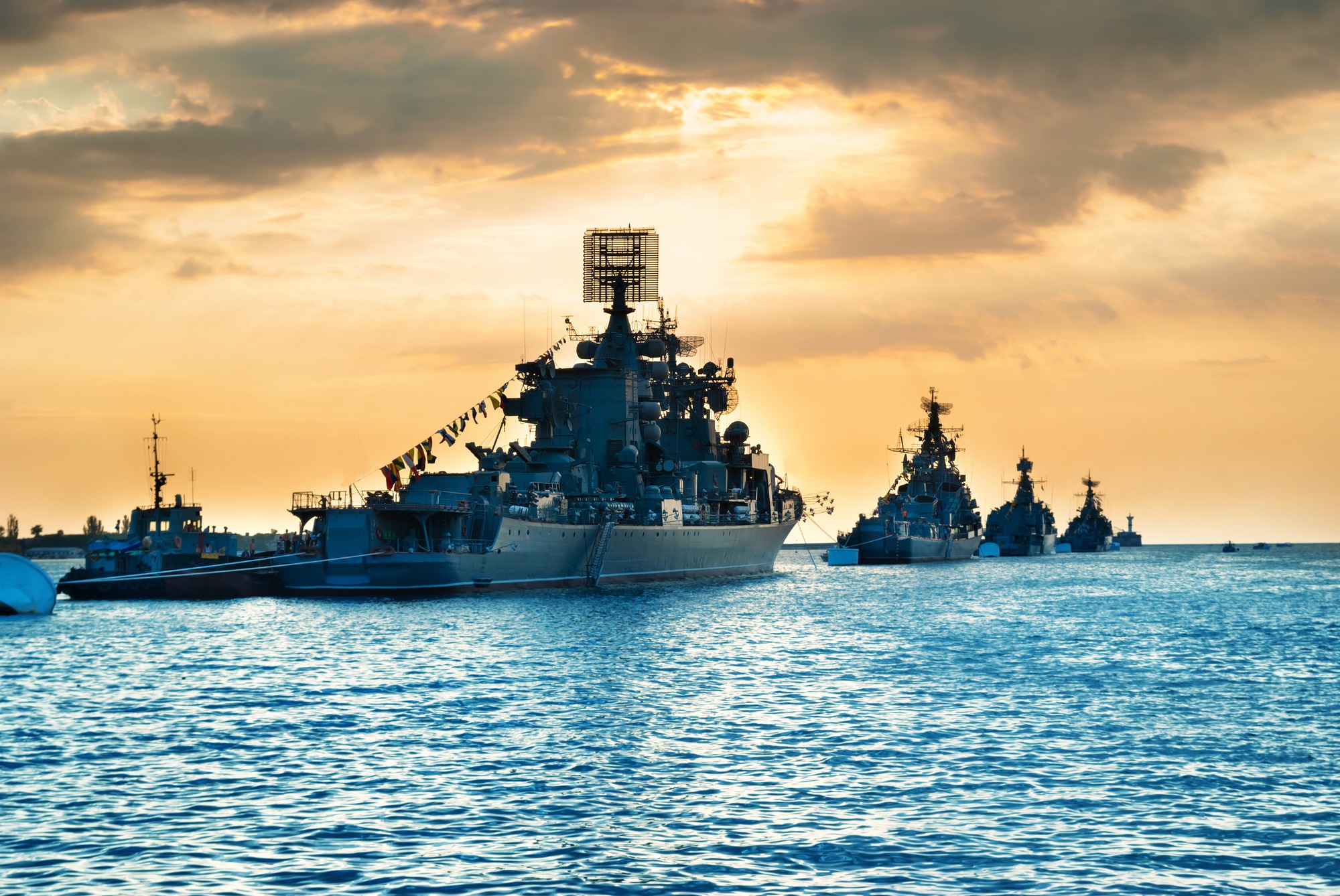 Military navy ships in a sea bay at sunset time
